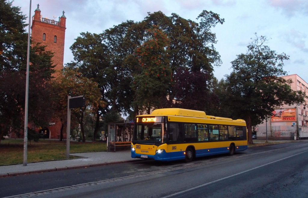 Městská doprava ve Słupsku, reprezentovaná Scanií na lince 1 v zastávce Grodzka, nalevo kostel sv. Mikuláše.